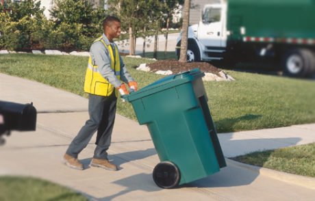 Waste collector pushing recycling bin